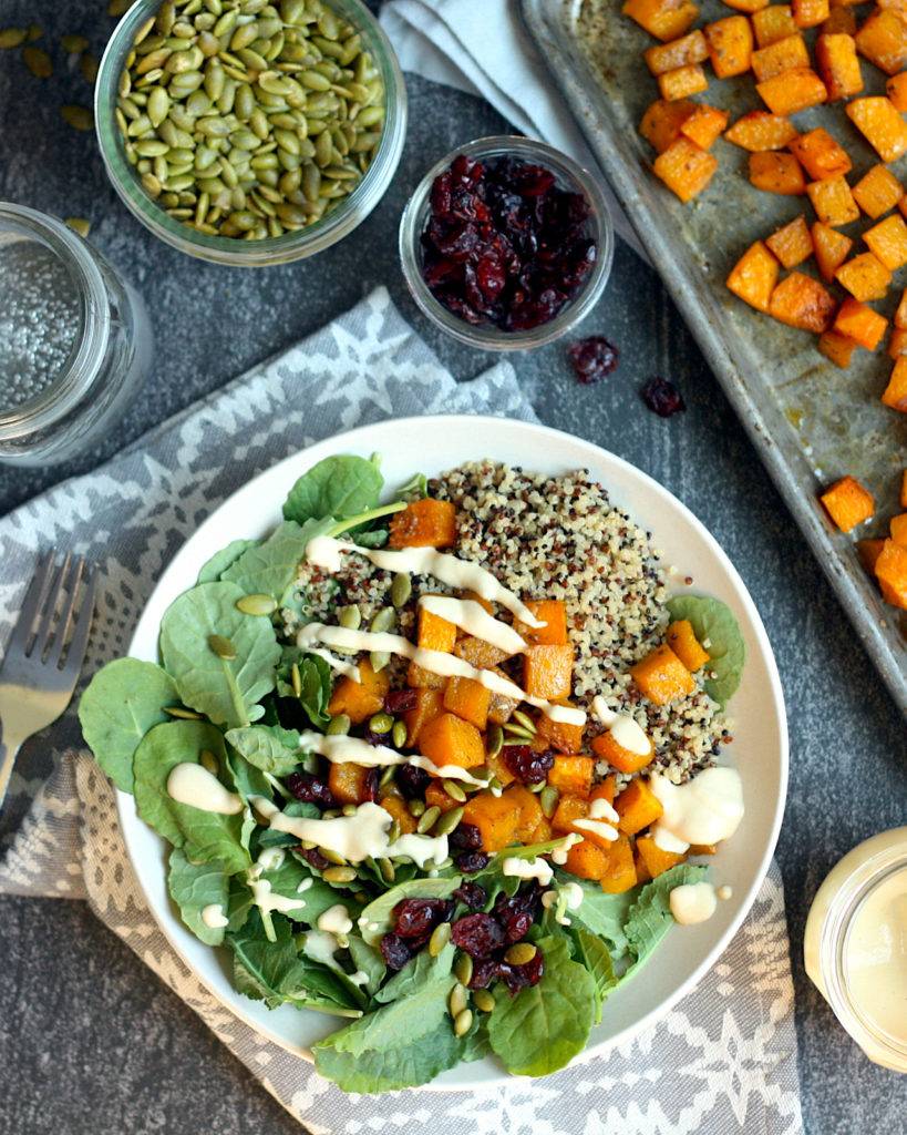 Quinoa grain bowls topped with roasted butternut squash, dried cranberries, toasted pepitas and maple-tahini dressing