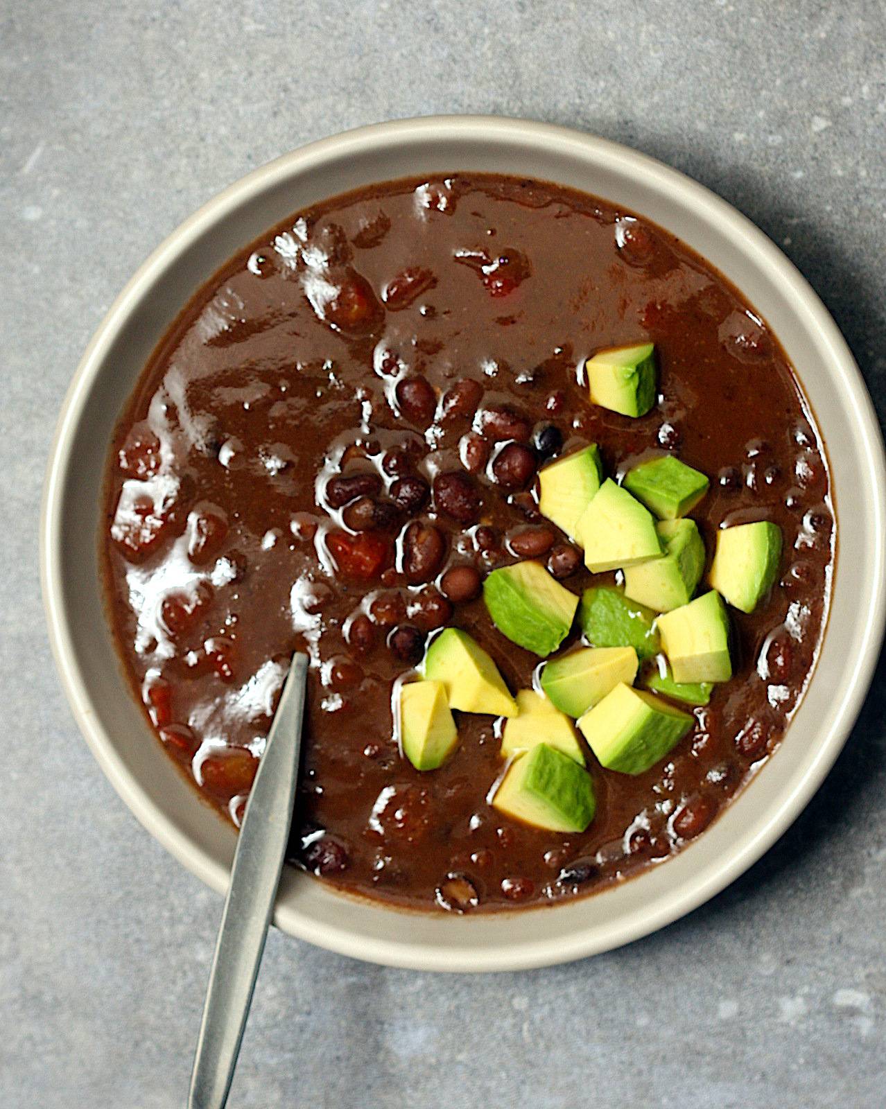 Bowl filled with black bean soup, topped with diced avocado